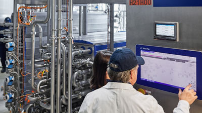 Employee operating a touchscreen beside stainless steel processing equipment
