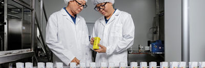 Two food production employees inspecting a carton package