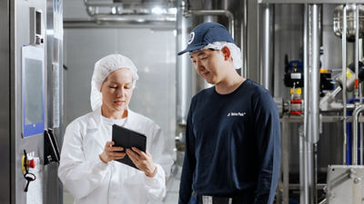 two employees looking at a tablet in factory
