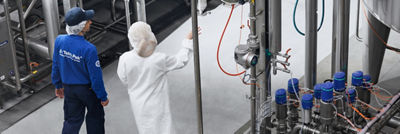 Two employees overlooking a processing facility, with one pointing towards the equipment