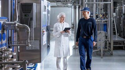 Two Tetra Pak employees reviewing operations on a tablet in a food processing facility