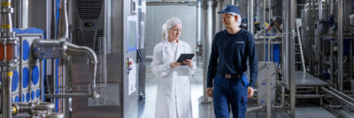 Two Tetra Pak employees reviewing production equipment using a tablet