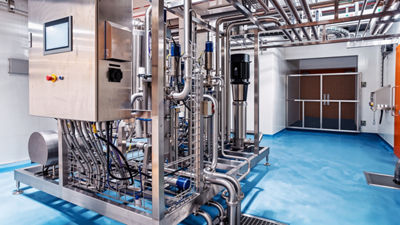 Stainless steel processing equipment and pipes inside an industrial facility.