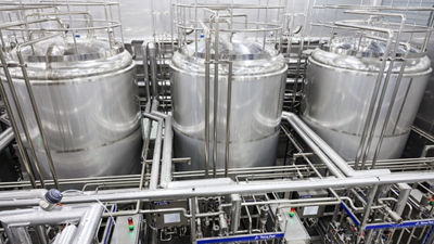 Large stainless steel processing tanks and piping in a food production facility