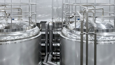 Stainless steel processing tanks surrounded by pipes, platforms and safety railings.