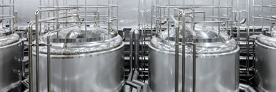 Stainless steel processing tanks surrounded by pipes, platforms and safety railings. 