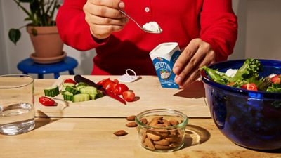 Person preparing food with a carton of dairy product.