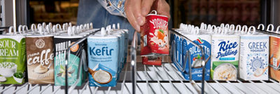 Person selecting a Tetra Reva package from a refrigerated supermarket shelf.