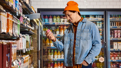 Person selecting a carton from a supermarket shelf.