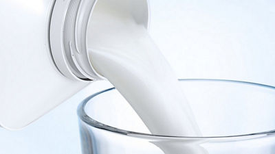 Vertido de leche en un vaso de un envase de cartón Tetra Top