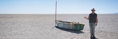干涸的湖面上一艘船旁边的男人