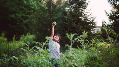 Boy holding a green pepper up in the air 