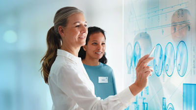Two women in front of large interactive screnn