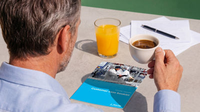 Tetra Pak upgrades case booklet on a table beside a man holding a cup of coffee