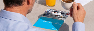 Tetra Pak upgrades case booklet on a table beside a man holding a cup of coffee