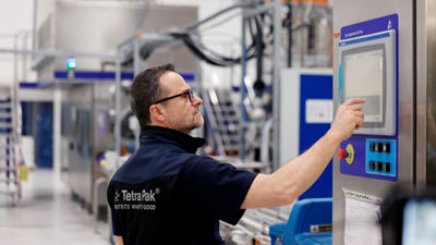 Tetra Pak technician operating a machine’s touchscreen in a production hall