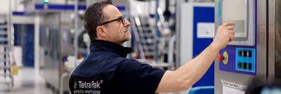 Tetra Pak technician operating a machine’s touchscreen in a production hall