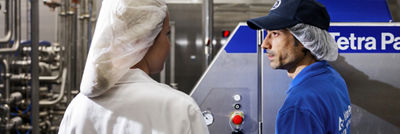 Two employees discussing equipment beside a Tetra Pak processing machine