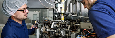 Two technicians inspecting the internal components of a production machine