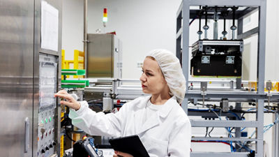 Woman operating a production machine’s touchscreen while holding a tablet