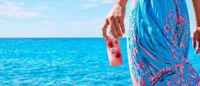 Woman at beach with health drink in Tetra Prisma Aseptic carton in her hand