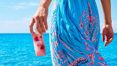 Woman at beach with health drink in Tetra Prisma Aseptic carton in her hand