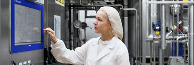 Femme dans une usine de production de fromage gérant un panneau de commande