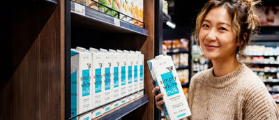 店内で牛乳のテトラ・ブリックアセプティック紙容器を手にする女性