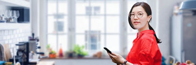 妇女用手机站在厨房