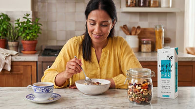 Woman in kitchen making breakfast, cereals and milk in carton package