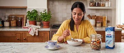 Woman in kitchen making breakfast, cereals and milk in carton package