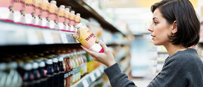 Une femme dans un magasin, regardant des boissons saines dans un rayon