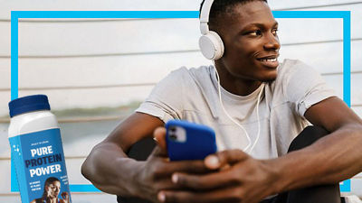 Young man with headphones and mobile phone, protein drink in Tetra Prisma Aseptic carton