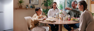 Family in kitchen having breakfast, chilled cartons on the table