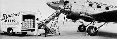 Man putting milk on conveyor belt from car to an airplane