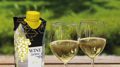 White wine carton with green grape design beside two filled wine glasses