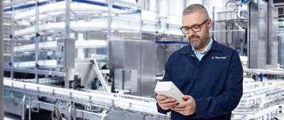 Hombre con gafas inspeccionando un envase en la fábrica de envasado