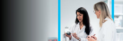 Two scientists in lab coats examining a device and discussing their findings in a laboratory setting.