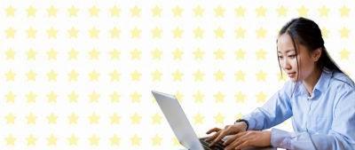 A imagem mostra uma mulher com uma camisa azul trabalhando compenetrada em seu laptop contra um fundo decorado com estrelas amarelas. A mulher está concentrada, sugerindo um ambiente de trabalho produtivo e envolvente. O fundo adiciona um tom alegre e otimista à imagem.
