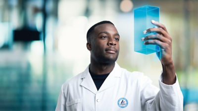 A scientist smiling while working with a microscope in a laboratory setting.