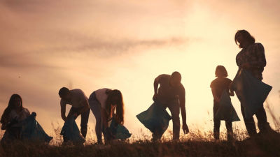 people collecting plastic in sunset