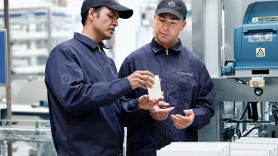 dos hombres con un envase observan una máquina