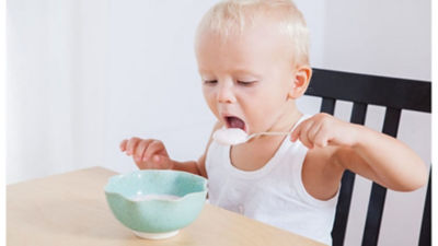 Um bebê comendo laticínios com colher