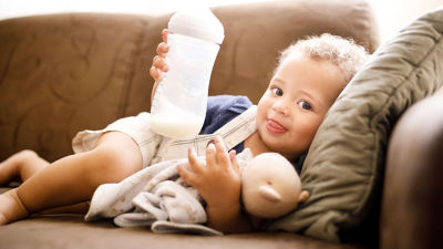 Baby in sofa with baby bottle