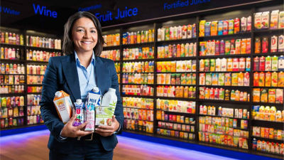 Woman holding drink packages in front of shelf