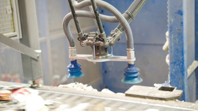 Closeup of robotic arm sorting cartons for recycling