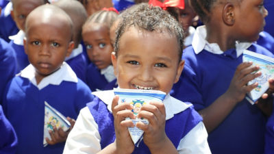 School girl smiling and drinking from Tetra Pak package
