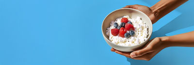 Hands holding a bowl with cottage cheese and berries