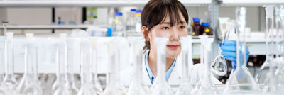 Woman in lab looking at glas bowl.