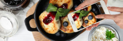 Person taking a mobile photo of food.